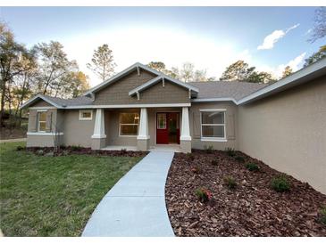 Inviting single-story home with a red front door, manicured landscaping, and a welcoming walkway at 6153 La Pine Rd, Brooksville, FL 34602