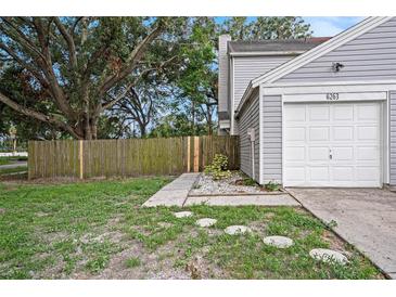 Charming home featuring a gray exterior, one car garage, and partially fenced yard at 6263 Oak Cluster Cir, Tampa, FL 33634