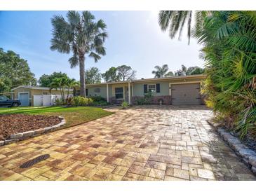 Charming single-story home with a well-maintained lawn, palm trees, and a brick-paved driveway at 6912 14Th N St # 6912, St Petersburg, FL 33702