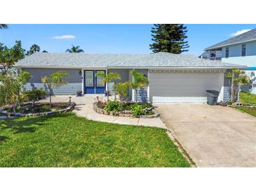 Charming single-story home featuring a well-manicured lawn and beautiful landscaping at 9917 San Sierra Way, Port Richey, FL 34668
