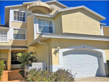 Two-story home with yellow siding, awning-covered window, and a white garage door at 1050 Starkey Rd # 106, Largo, FL 33771