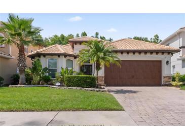 Charming single-story home featuring a tile roof, brick driveway, and lush tropical landscaping at 10880 Cory Lake Dr, Tampa, FL 33647