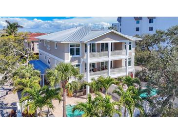 Beautiful three-story home featuring balconies, a pool, and lush palm trees surrounding the property at 1204 Derby Ln, Sarasota, FL 34242