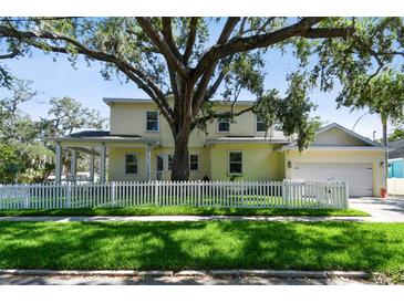 Charming two-story home featuring a white picket fence, lush lawn, and mature tree providing ample shade at 238 7Th S Ave, Safety Harbor, FL 34695