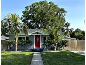 Charming single-story home with a vibrant red door, lush landscaping, and two palm trees accenting the front yard at 3980 55Th N Ave, St Petersburg, FL 33714