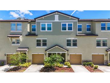 Exterior shot of multiple townhomes with tan garages and landscaping, featuring an appealing facade at 4567 Tuscan Loon Dr, Tampa, FL 33619