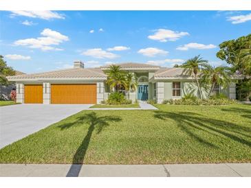 Beautiful one-story home with a large two car garage, a light green exterior, and tropical landscaping at 5002 E Longboat Blvd, Tampa, FL 33615