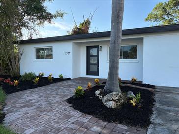 Charming single-story home featuring a newly landscaped yard with vibrant plants and brick paver walkway at 7703 Glenview Ln, Tampa, FL 33615