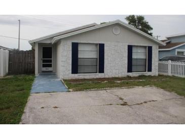 Charming single-story home featuring a stone facade, blue shutters, and a well-maintained front yard at 8234 Ravencroft Dr, Tampa, FL 33615