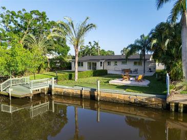 Waterfront backyard with a dock, patio, and manicured lawn and landscaping on a sunny day at 243 45Th Ne Ave, St Petersburg, FL 33703