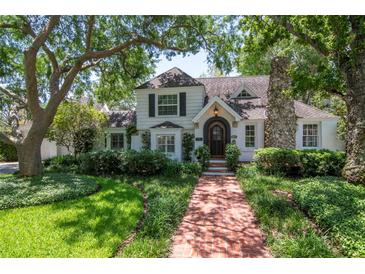 Charming two-story home with a brick walkway, mature trees and a stone chimney at 560 Bosphorous Ave, Tampa, FL 33606