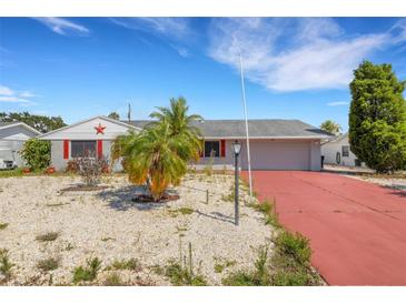 Charming single-story home featuring a cozy facade, red-painted driveway, and xeriscaped yard with a palm tree at 638 La Jolla Ave, Sun City Center, FL 33573