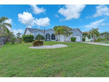 Landscaped home featuring lush green lawn, stone garden, mature trees, and charming curb appeal at 832 Birdie Way, Apollo Beach, FL 33572
