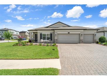 Charming home featuring a well-manicured lawn, three-car garage, and inviting front patio at 20108 Stone Pine Cir, Lutz, FL 33558