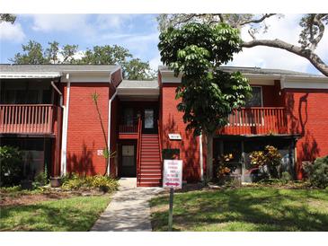 Two-story red brick building with well-maintained landscaping and stairs leading to second-floor units at 8220 12Th N Way # H, St Petersburg, FL 33702