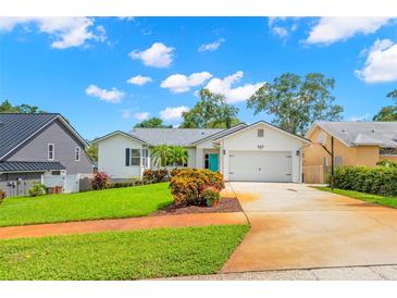 Charming single-story home with well-manicured lawn, a vibrant turquoise door and an attached garage at 859 Harbor Hill Dr, Safety Harbor, FL 34695