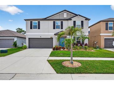 Two-story home with a well-manicured lawn, grey paint, black shutters, and a two-car garage at 12835 Wildflower Meadow Dr, Riverview, FL 33579