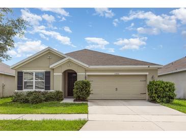 Charming single-story home featuring a two-car garage, well-manicured lawn, and classic architectural details at 15406 Gopher Trop Pl, Sun City Center, FL 33573
