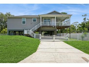 Inviting two-story home with a spacious covered porch and a well-manicured front lawn and white picket fence at 9107 Brunswick Ln, Tampa, FL 33615