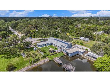 Waterfront home featuring a dock, lush landscaping, and unique architectural design with solar panels at 9938 Alavista Dr, Gibsonton, FL 33534