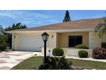 Charming home featuring a landscaped yard, patterned driveway, and attached two-car garage at 205 Strong Bow Ct, Sun City Center, FL 33573
