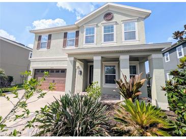 Charming two-story home featuring a covered front porch and a well-manicured, landscaped front yard at 32599 Natural Bridge Rd, Wesley Chapel, FL 33543