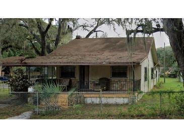Modest one-story home with a covered porch and overgrown landscaping needs major repairs at 4009 N 15Th St, Tampa, FL 33610