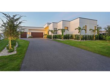 Modern home with paver driveway, manicured lawn, and lush landscaping at 501 Barcelona Dr, Tierra Verde, FL 33715
