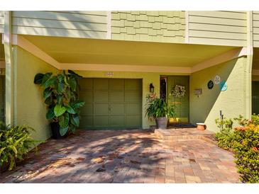 Inviting condo exterior showcasing a garage and charming front door with brick-paved parking at 505 Sandy Hook Rd # 505, Treasure Island, FL 33706