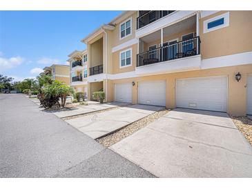 Three-story condo building with attached garages, driveways, and balconies on a sunny day at 5065 Royal Palms Way # 303, New Port Richey, FL 34652