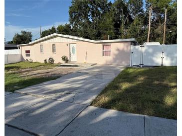 Charming pink brick home with a well-maintained lawn and a concrete driveway at 5601 Golden Dr, Tampa, FL 33634