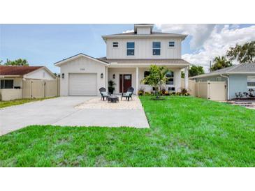 Charming two-story home with a manicured lawn and cozy outdoor seating area in front at 1410 Nebraska Ave, Palm Harbor, FL 34683