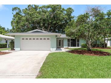 Charming single-story home with a well-manicured lawn, mature trees and a two car garage at 1960 Canadiana Ct, Dunedin, FL 34698