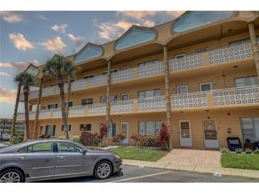 A tan condominium building is shown with palm trees, balconies, and tropical plants at 2466 Ecuadorian Way # 32, Clearwater, FL 33763