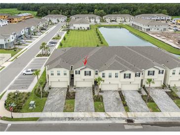 A beautiful aerial view of these townhomes near a body of water within a well-manicured community at 26082 Woven Wicker Bnd, Lutz, FL 33559