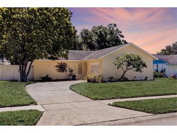 Charming one-story home with a well-manicured lawn and mature tree at 310 Arbor E Dr, Palm Harbor, FL 34683