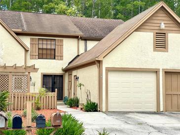 Beige two-story townhome with two car garage, shuttered windows and tidy landscaping at 4006 Huxford Ct, Tampa, FL 33624