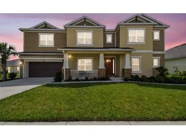 Inviting two-story home featuring a covered front porch and well-manicured lawn at 7024 Bradbury Cir, Wesley Chapel, FL 33545