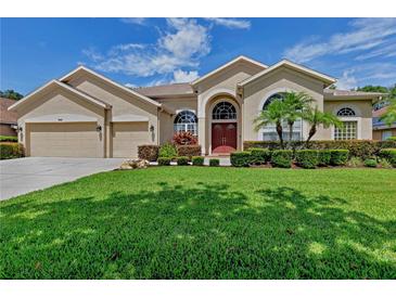 Charming single-Gathering home featuring a manicured lawn, mature landscaping, and a welcoming three-car garage at 9242 Brindlewood Dr, Odessa, FL 33556