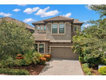 Inviting two-story home with a tile roof, brick driveway, and lush landscaping at 1391 Marinella Dr, Palm Harbor, FL 34683