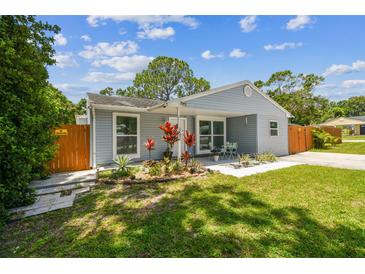 Charming single story home with light blue siding, landscaped yard, and a cozy covered front porch at 2692 Cedarbrooke Dr, Palm Harbor, FL 34684