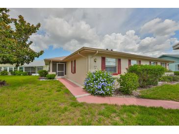 Charming single-story home featuring a well-maintained lawn, colorful flowers, and red shutters at 304 Fowling Ct # A, Sun City Center, FL 33573