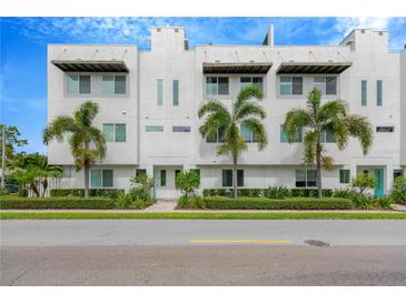Modern townhome featuring a clean, minimalist design, complemented by lush palm trees and manicured landscaping at 3100 W Paul Ave # 14, Tampa, FL 33611