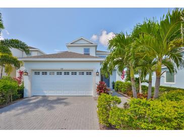 Charming two-story home with a brick driveway, a two-car garage and lush tropical landscaping at 314 Blackrock Ln, Apollo Beach, FL 33572