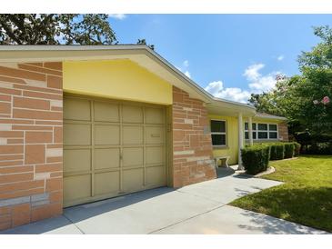 Tan garage door of yellow house with stacked stone facade and sunny skies at 4407 Westwood Dr, Holiday, FL 34691