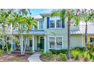 Inviting two-story home featuring a manicured lawn, columns, and a charming walkway to the front door at 5518 Luminar Pointe Ln, Apollo Beach, FL 33572