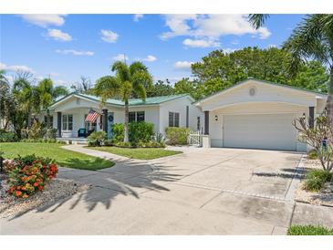 Charming home featuring a lovely landscaped yard, palm trees, and a welcoming front entrance and attached garage at 759 Lantana Ave, Clearwater Beach, FL 33767