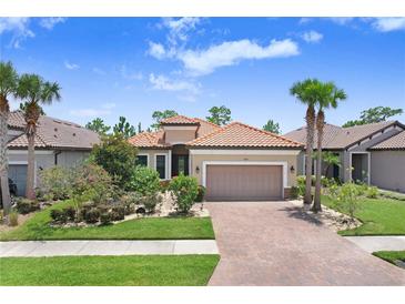 Beautiful single-story home featuring a brick driveway, lush landscaping, and a classic tile roof at 8605 Grand Alberato Rd, Tampa, FL 33647