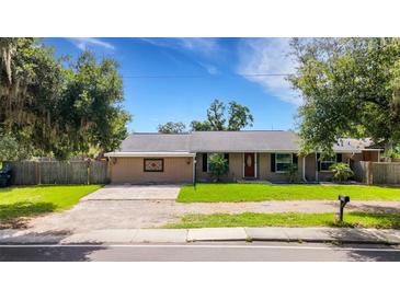 Cozy single story home featuring a red front door, green lawn, and mature trees at 915 S Miller Rd, Valrico, FL 33594