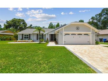 Charming single-story home with well-manicured lawn and a brick-paved driveway leading to an attached two-car garage at 15108 Winterwind Dr, Tampa, FL 33624